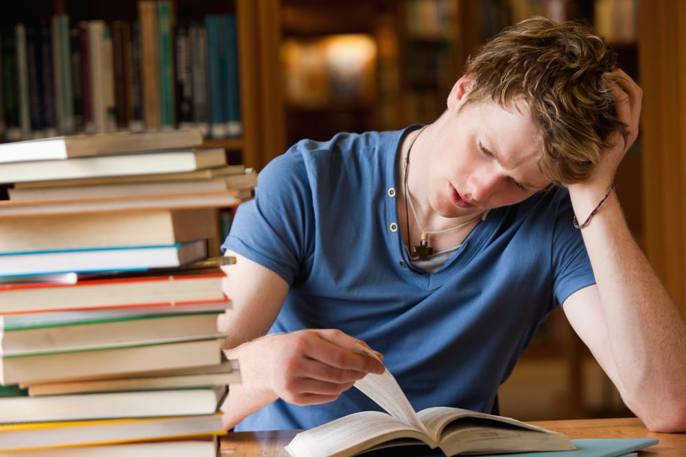 Tired man reading a book in a library